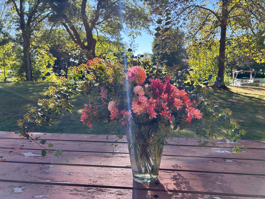 Vase with flowers on a wooden table outdoors